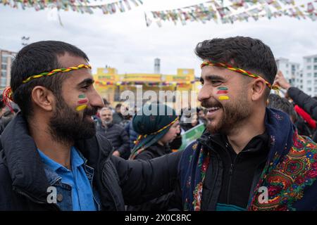 Diyarbakir, Türkei. März 2024. Zwei junge Männer werden bei einer Kundgebung mit gemalten Fahnen im Gesicht gesehen. Hunderttausende von Menschen besuchen Diyarbakir Newroz, um Newroz zu feiern, das die Ankunft des Frühlings und des neuen Jahres symbolisiert. Da es verboten ist, gelbe, grüne und rote Fahnen in Newroz zu bringen, malten die Menschen ihre Gesichter in gelben, roten und grünen Farben. (Foto: Bilal Seckin/SOPA Images/SIPA USA) Credit: SIPA USA/Alamy Live News Stockfoto