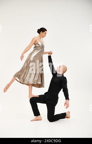 Ein junger Mann in Schwarz und eine junge Frau in einem Kleid tanzen anmutig zusammen, mit akrobatischen Elementen. Stockfoto