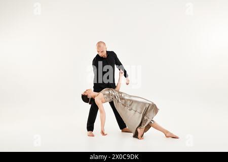 Ein junger Mann in Schwarz und eine junge Frau in einem Kleid tanzen als Paar mit akrobatischen Elementen. Studio auf weißem Hintergrund. Stockfoto