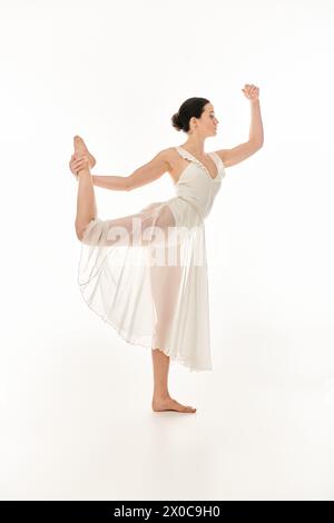 Eine junge Frau bewegt sich anmutig in einem weißen Kleid und strahlt Eleganz und Freude aus in einem Studio auf weißem Hintergrund. Stockfoto