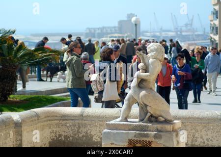 Tarragona, Spanien - 11. April 2024: Dieses Bild zeigt eine exquisite Statue, die eine intime Umarmung mit dem ruhigen Meer und der lebhaften Menschenmenge darstellt Stockfoto