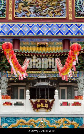 Ein Gebäude mit roten Laternen, die vom Dach hängen. Die Laternen sind mit chinesischen Schriftzeichen dekoriert und beleuchtet, was ein festliches und lebhaftes A schafft Stockfoto