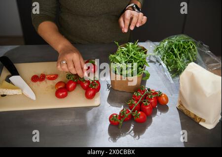 Blick von oben auf eine Hausfrau, die an der Küchentheke mit frischen Reifen Bio-Zutaten steht und einen gesunden Salat für das Abendessen oder die Mittagspause zubereitet Stockfoto