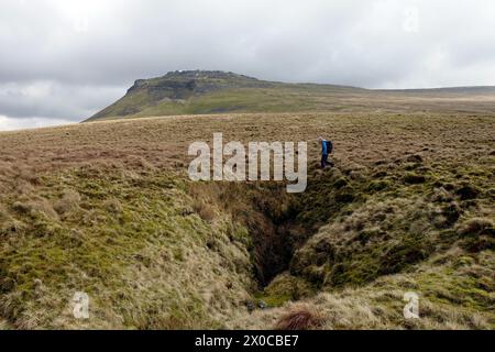 Mann (Wanderer) Walking by Pot Hole in der Nähe von Tatham Wife Moss unter dem Ingleborough Mountain im Yorkshire Dales National Park, England, Großbritannien. Stockfoto