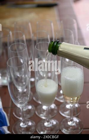 Eine Flasche Champagner wird in eine Reihe von Weingläsern gegossen. Das Konzept des Feierns und Genusses Stockfoto