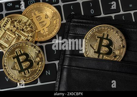 Bitcoin Kryptowährung Goldmünzen in schwarzer Brieftasche auf Laptop. Stockfoto