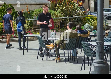 Tarragona, Spanien - 11. April 2024: Junges Paar genießt in einem Café im Freien in Tarragona, mit entspannter Atmosphäre und moderner Architektur im bac Stockfoto