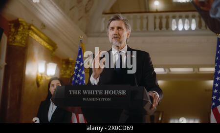 Der Präsident der Vereinigten Staaten spricht während der Pressekonferenz eine politische Rede. Minister spricht mit Journalisten im Weißen Haus, gibt Interview für die Medien. Amerikanische Fahnen im Hintergrund. Stockfoto