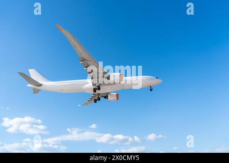 Flugzeug Passagierflugzeug mit ausgefahrenem Fahrwerk fliegt auf blauem Himmel, Seitenansicht. Stockfoto