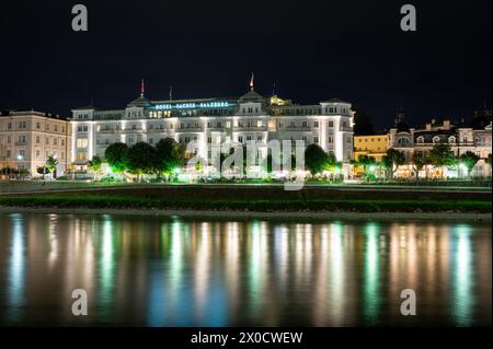 Salzburg, Österreich, 15. August 2022. Ikonisches Nachtbild des Luxushotels Sacher, das sich im Wasser der Salzach spiegelt. Kopierbereich. Stockfoto