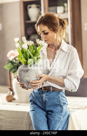 Die Hausfrau genießt einen Haufen Blumen und das Innere des Wohnzimmers. Glückliche Frau genießt Tulpenstrauß. Stockfoto