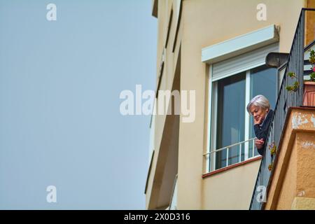 Tarragona, Spanien - 11. April 2024: Eine ältere Frau genießt die Ruhe des morgens von ihrem Balkon in Tarragona und schafft ein Bild der Ruhe Stockfoto