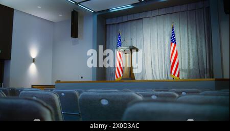 Tribune für den Präsidentschaftskandidaten der Vereinigten Staaten im Weißen Haus. Presseraum mit Sitzen und amerikanischen Flaggen. Konferenzdebatte mit Mikrofonen auf der Bühne. Stockfoto