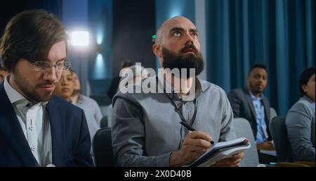 Verschiedene Medienvertreter heben die Hände und schreiben Antworten in Notizbüchern von Präsidenten oder Politikern im Konferenzsaal des Regierungsgebäudes. Journalisten stellen während der Pressekampagne Fragen. Stockfoto