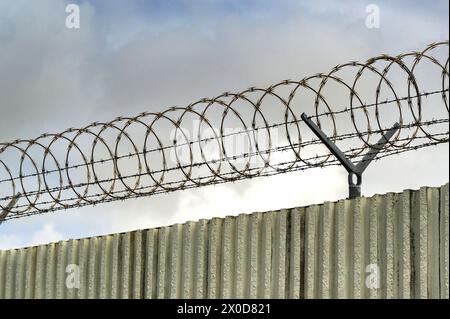 Spulen aus Stacheldraht auf einem Zaun für die Sicherheit und den Schutz der Räumlichkeiten Stockfoto