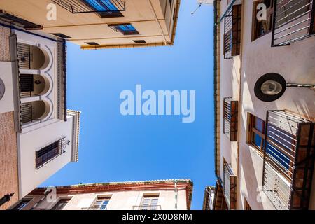 Blick nach oben auf eine sehr enge Straßenkreuzung der Stadt Malaga in Andalusien, Spanien. Stockfoto