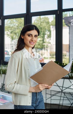 Eine Geschäftsfrau untersucht in einem modernen Büro ein Klemmbrett an einem schlanken Fenster und verkörpert ein bahnbrechendes Franchise-Konzept. Stockfoto