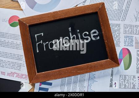 Eine Tafel, auf der das Wort Franchise in feiner Kreide steht, symbolisiert Geschäftswachstum und Wachstum in einem modernen Büroumfeld. Stockfoto