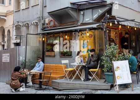 Istanbul, Türkei - 10. April 2024, Menschen sitzen während des Ramadan auf der Veranda eines Cafés im Bezirk Balata. Junge Leute fotografieren einander Stockfoto