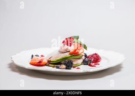 Köstliches und gesundes Frühstück mit Pfannkuchen, Früchten und Beeren auf weißem Teller. Isoliert. Konzept für gesunde Ernährung. Stockfoto