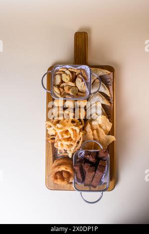 Bierplatte mit Blick von oben mit Croutons, Zwiebelringen, Chips auf einem Holzbrett. Stockfoto