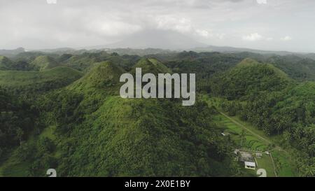 Asia Green Hill aus der Vogelperspektive: Grün hügelig niemand Landschaft auf dem Land Legazpi, Philippinen. Ferienhaus am Hang Gras Tal. Epische wilde Natur an bewölktem Sommertag. Asiatische grüne grasbewachsene Berge Stockfoto