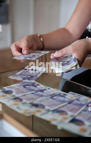 Frau, die zu Hause Bargeld zählt- Notfallbudgetierung, Sparselektive Fokussierung Stockfoto