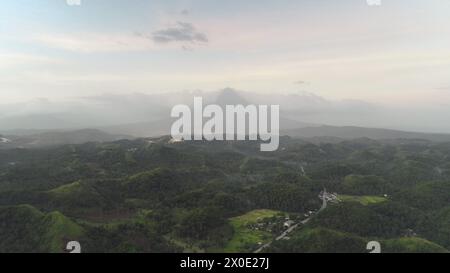 Blick aus der Vogelperspektive auf die Stadt im Dorf am Hügel. Kleine Cottages an der Landstraße bewundern hügelige grüne Landschaft mit tropischen Pflanzen. Andere urbane Landschaft Legazpi Stadt, Albay Provinz, Philippinen, Asien Stockfoto