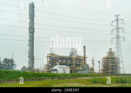 Eine Ölraffinerie steht mitten auf einem riesigen Feld, mit Rohren und Strukturen, die am Himmel sichtbar sind. Stockfoto
