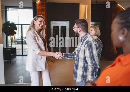 Mann und Frau schütteln vor einer Tür die Hand Stockfoto