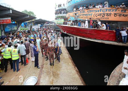 Mindestens 5 Tote bei einem Schiffsunfall in Dhaka Feuerwehrleute, Sicherheitsbeamte und örtliche Menschen versammeln sich nach einem Schiffsunfall am Sadarghat Schiffsterminal in Dhaka, Bangladesch am 11. April 2024. Nach Angaben der Flusspolizei wurden mindestens fünf Menschen getötet, nachdem ein Schiffseil bei einem Parkversuch von einem anderen Schiff am Sadarghat Schiffsterminal in Dhaka abgerissen wurde. Dhaka Dhaka Bezirk Bangladesch Copyright: XHabiburxRahmanx Stockfoto