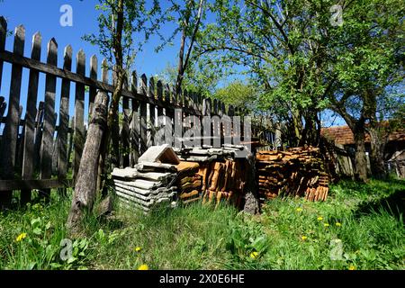 Verwitterte Dachziegel auf dem alten Bauernhof, friedliches Stilleben des Zauns in der Sonne auf grünem Gras, traditioneller Bauernhof in Boljanic, Doboj, Republik Srpska Stockfoto