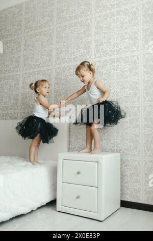 Zwei junge Mädchen spielen fröhlich auf einem Bett, lächeln und lachen, während sie gemeinsam springen und herumhüpfen. Stockfoto