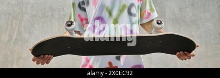 Ein junger Skater mit einem Skateboard im Freien in einem sonnigen Skatepark, der sich auf eine aufregende Fahrt an einem Sommertag vorbereitet. Stockfoto