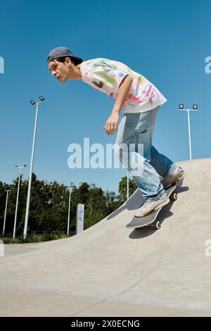 Ein junger Mann gleitet an einem sonnigen Sommertag mühelos die Rampe auf seinem Skateboard in einem belebten Outdoor-Skatepark hinunter. Stockfoto