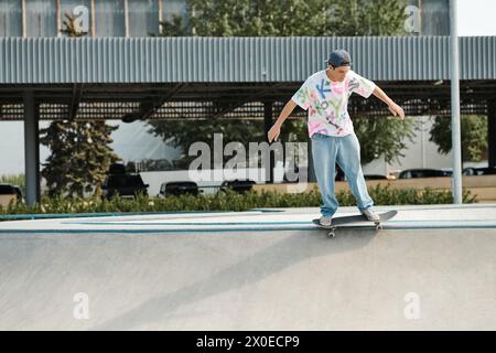 Ein junger Skaterjunge reitet an einem sonnigen Sommertag furchtlos an einer Rampe in einem Skatepark im Freien entlang. Stockfoto