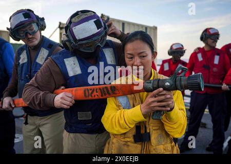 Pazifik. März 2024. Boatswains Mate 2. Klasse Yin Su, rechts, aus Muse, Myanmar, unterweist die US-Marines, der Alpha Company, 15th Marine Expeditionary Unit (MEU), wie man die Düse eines Feuerwehrschlauchs während einer Feuerwehrübung auf dem Flugdeck an Bord des Amphibiendocks USS Harpers Ferry (LSD 49) auf dem Weg im Pazifischen Ozean am 21. März 2024 bemannt. Harpers Ferry führt derzeit Routineoperationen in der 3. US-Flotte mit Elementen der 15. MEU durch. (Foto von Sang Kim) (Foto: © U.S. Navy/ZUMA Press Wire) NUR REDAKTIONELLE VERWENDUNG! Nicht Stockfoto