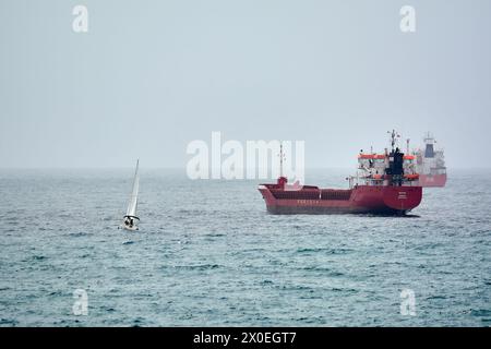 Tarragona, Spanien - 11. April 2024: Das Bild fängt die ruhige Essenz des Hafens von Tarragona mit aufgereihten Segelbooten und Frachtschiffen ein Stockfoto