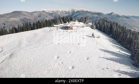 Luftkurort im schneebedeckten Bergwald. Touristen Wahrzeichen in der Naturlandschaft. Frost und kalter, sonniger Tag. Sonnenschein über der Skipiste. Menschen Aktivurlaub in Karpaten, Bukovel, Ukraine, Europa Stockfoto