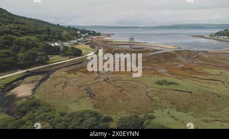 Zeitlupe der schottischen Whisky-Destillerie in Village Aerial. Straße, Hütten, Häuser im grünen Bergtal. Sommer bewölkter Tag. Keine Naturlandschaft auf Arran Island, Schottland. Filmdrohnenaufnahme Stockfoto