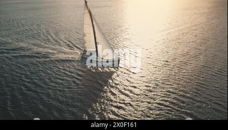 Sonnenyachten mit weißen Segeln in der offenen Meeresoberfläche. Segeln am sonnigen Sommertag. Segeln auf Segelbooten an der Meeresbucht. Luxuriöser Lebensstil mit ruhigem und entspannendem Konzept. Eine ruhige, filmische Landschaft Stockfoto