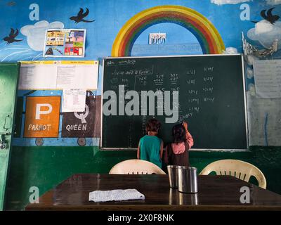 Zwei Kinder schreiben an der Tafel in der ländlichen Grundschule von Indien. Das sind Schüler der 2. Klasse der staatlichen Grundschule in Indien. Datum: Stockfoto