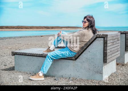 49-jährige Russin, die an einem frühen Frühlingstag auf einer Bank vor dem japanischen Meer sitzt Stockfoto