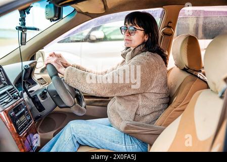 Junge attraktive 49-jährige Frau im Jackett, die wegschaut und das Auto fährt Stockfoto