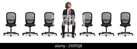 Leere Bürostühle und ein junger professioneller Mann, der in der Mitte sitzt und isoliert auf weißem Hintergrund aufblickt Stockfoto