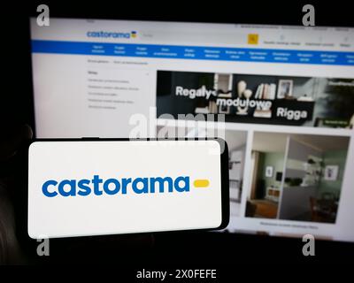 Person mit Smartphone und Logo der Filialkette Castorama vor der Website. Schwerpunkt auf dem Display des Telefons. Stockfoto