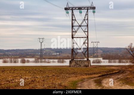 Stromleitmasten stehen in einem von Hochwasser überfluteten Feld. Stockfoto