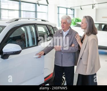 Ein älteres kaukasisches Paar wählt ein neues Auto in einem Autohändler. Stockfoto