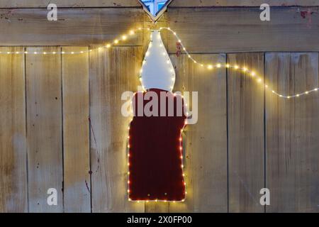 Beleuchtete Kerze vor einer Holzwand Stockfoto