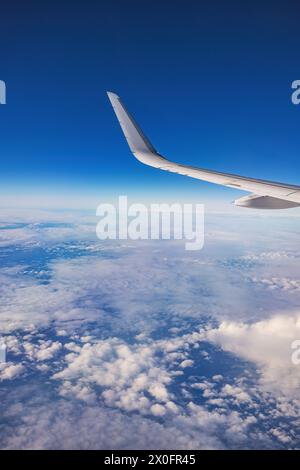 Das Flugzeug fliegt über farbigen Wolken bei Sonnenuntergang oder Sonnenaufgang Wolkenlandschaft, Blick vom Flugzeugfenster aus auf Flügelturbinen und Horizont Stockfoto